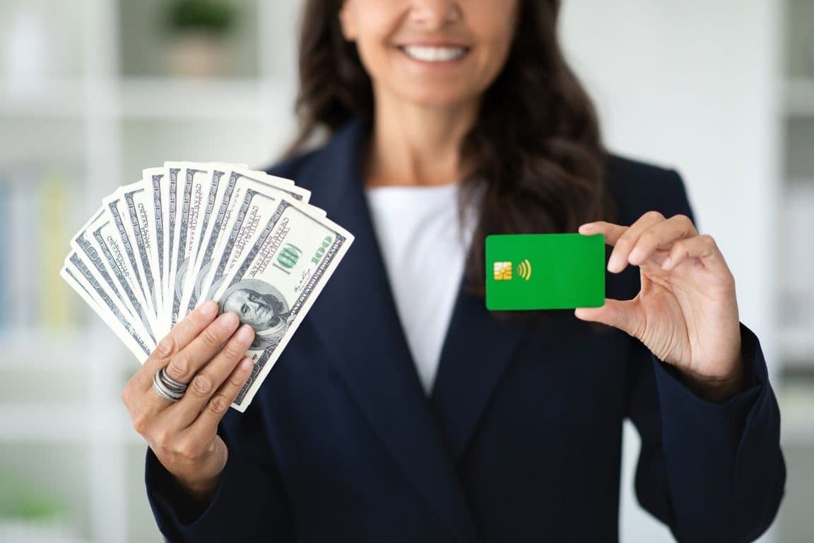 A woman holding up cash in one hand and a card in the other.